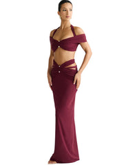 Woman wearing a burgundy evening gown with cut-out design on a white background