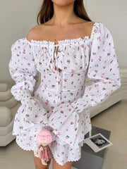 Woman wearing a white floral dress with long sleeves in an indoor setting.