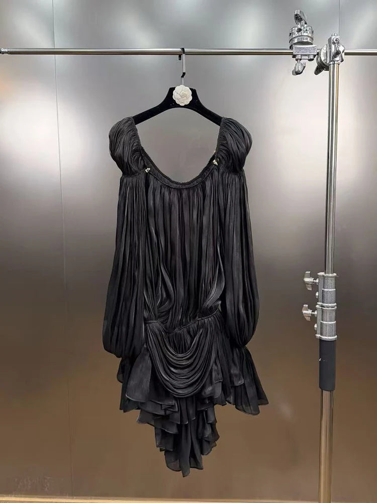 Black dress hanging on a rack against a reflective wall
