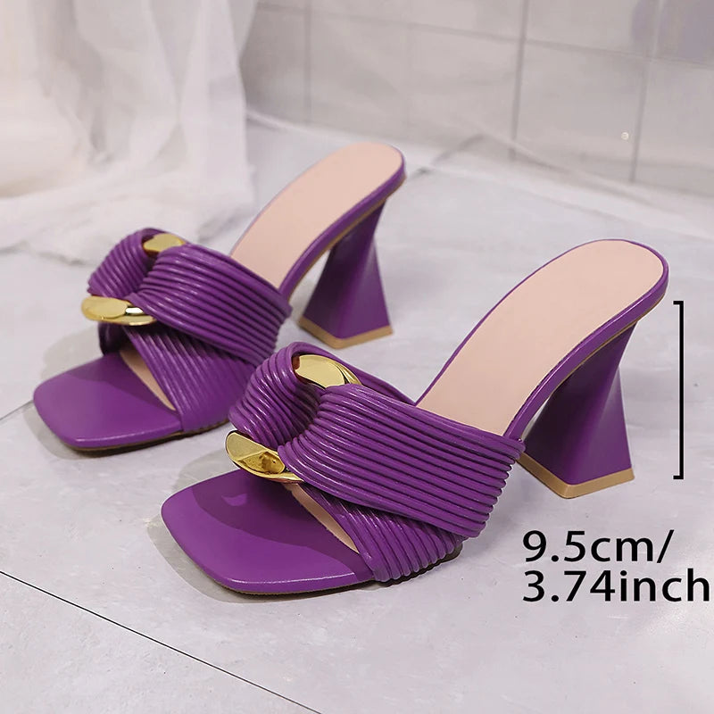 Purple high-heeled sandals with gold accents on a light gray background