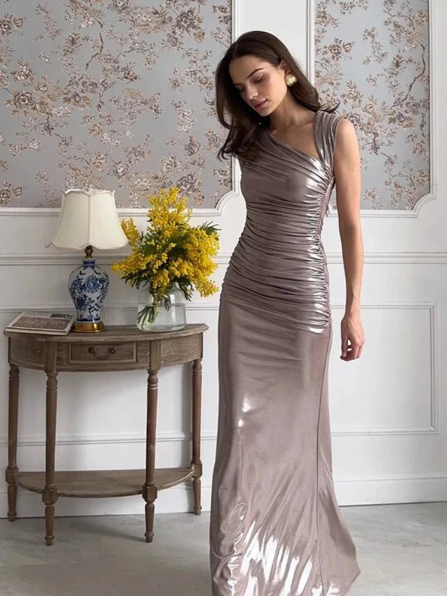 Woman in a metallic silver dress standing in a room with floral wallpaper and a side table.