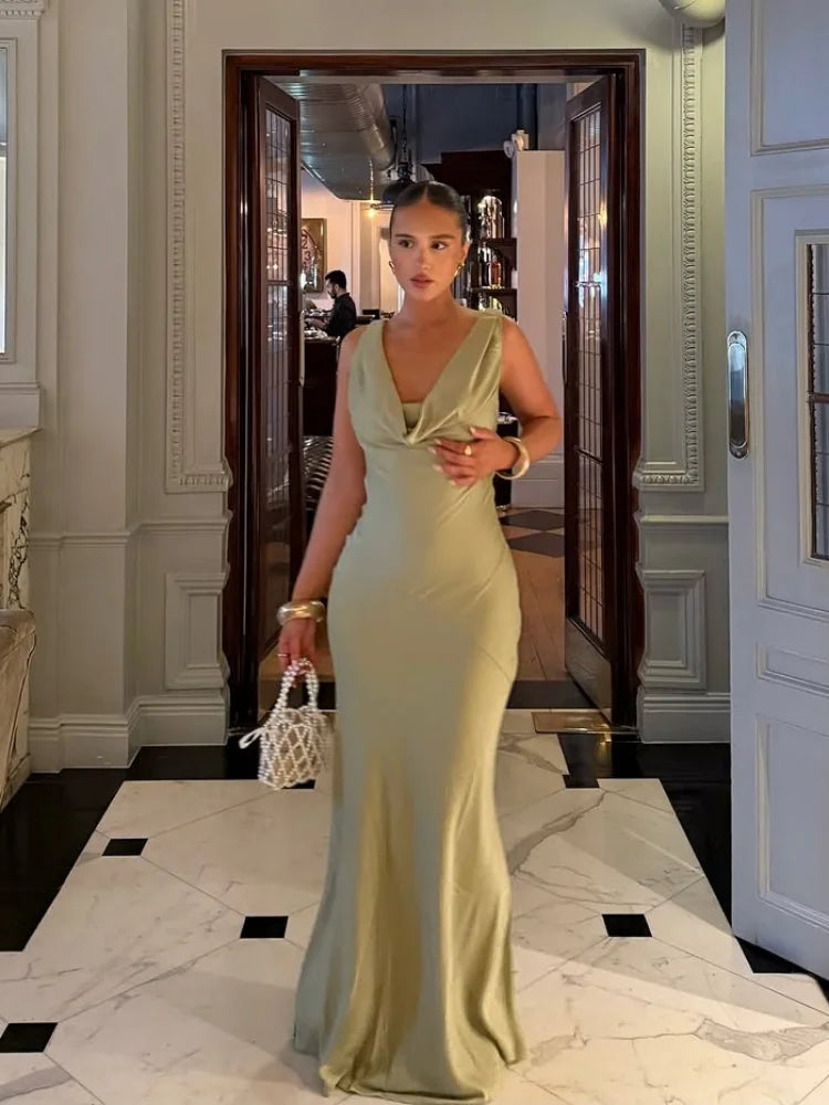 Woman in a light green evening gown standing in an elegant interior setting.