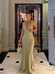 Woman in a light green evening gown standing in an elegant interior setting.