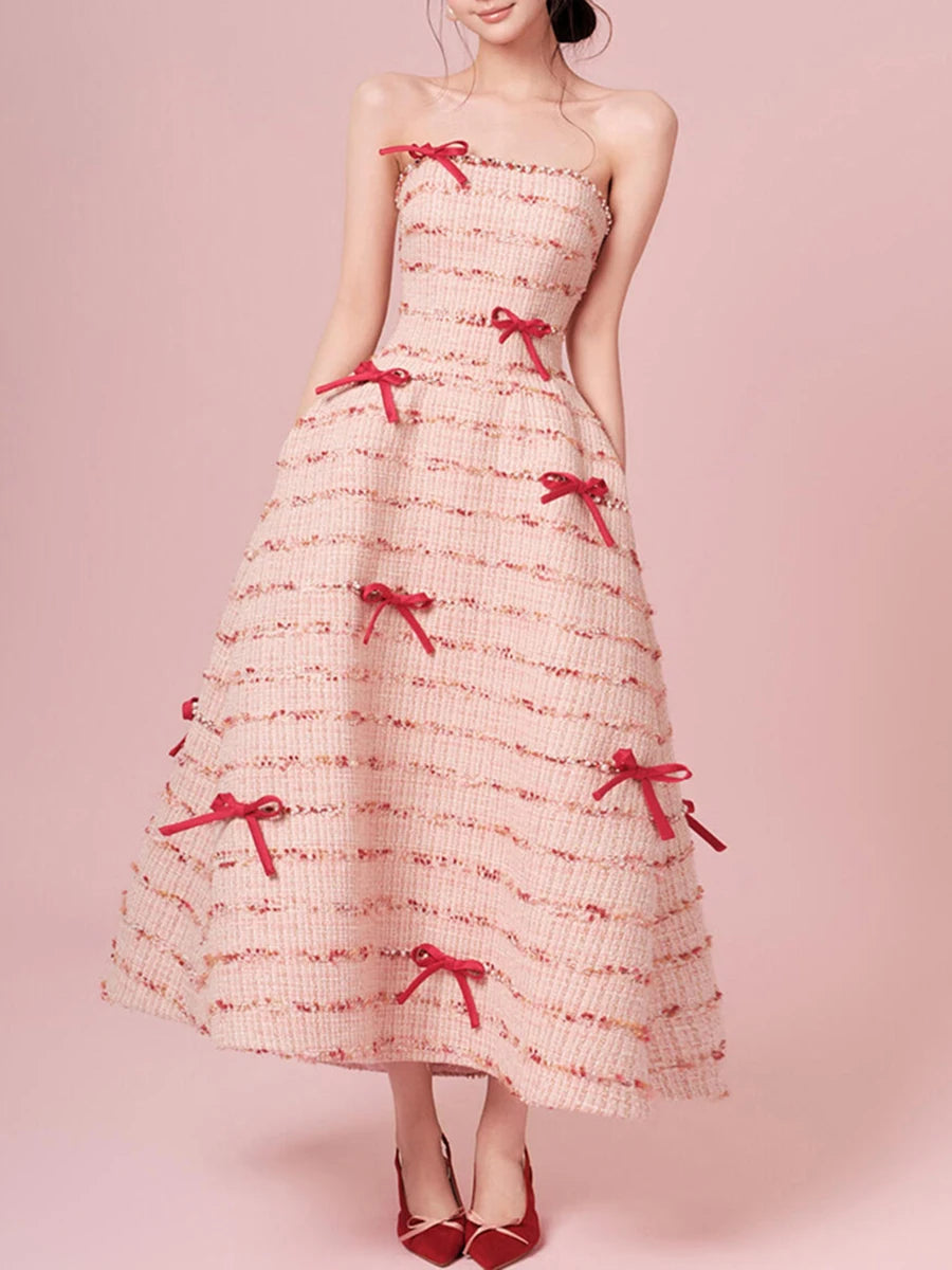 Woman wearing a pink dress with red bows on a pink background