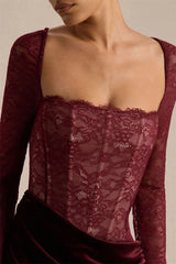 Close-up of a burgundy lace top with long sleeves on a neutral background