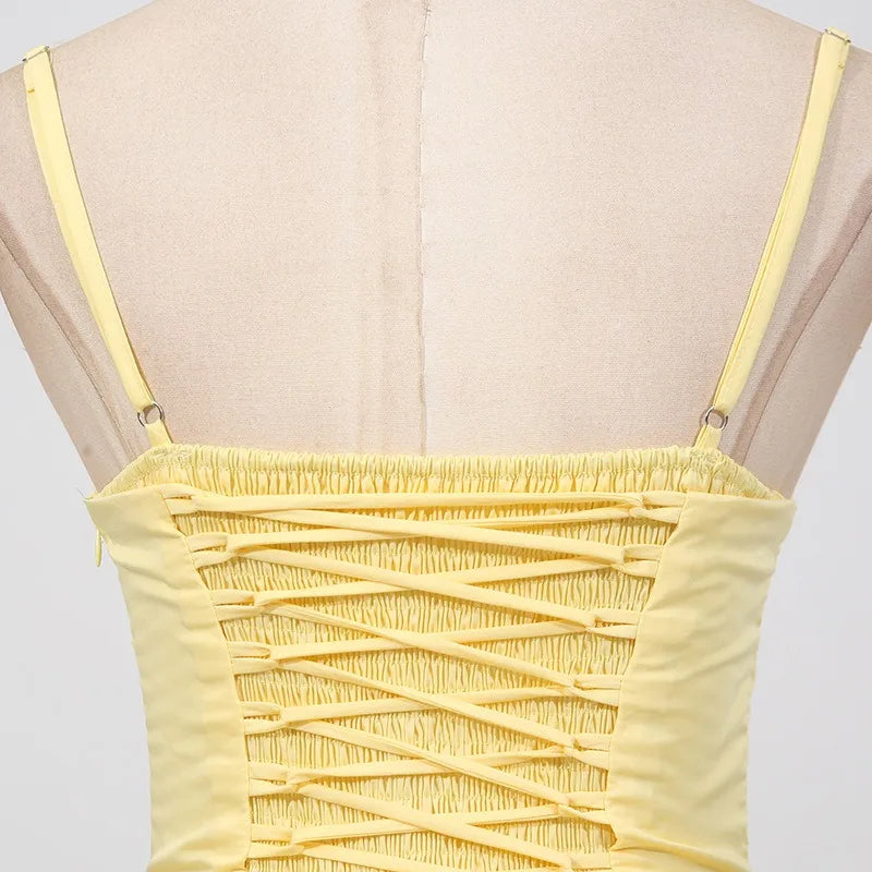 Yellow strappy top on a mannequin with a plain background
