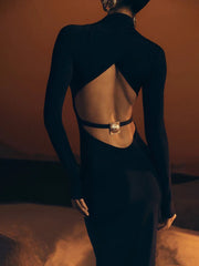 Person wearing a black outfit with cut-out design and gold belt against a warm-toned background