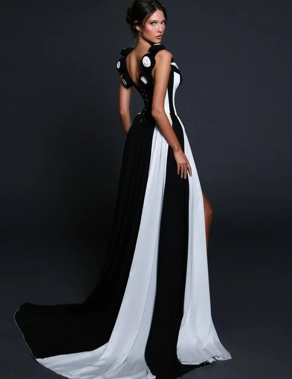 Woman wearing a black and white evening gown against a dark background