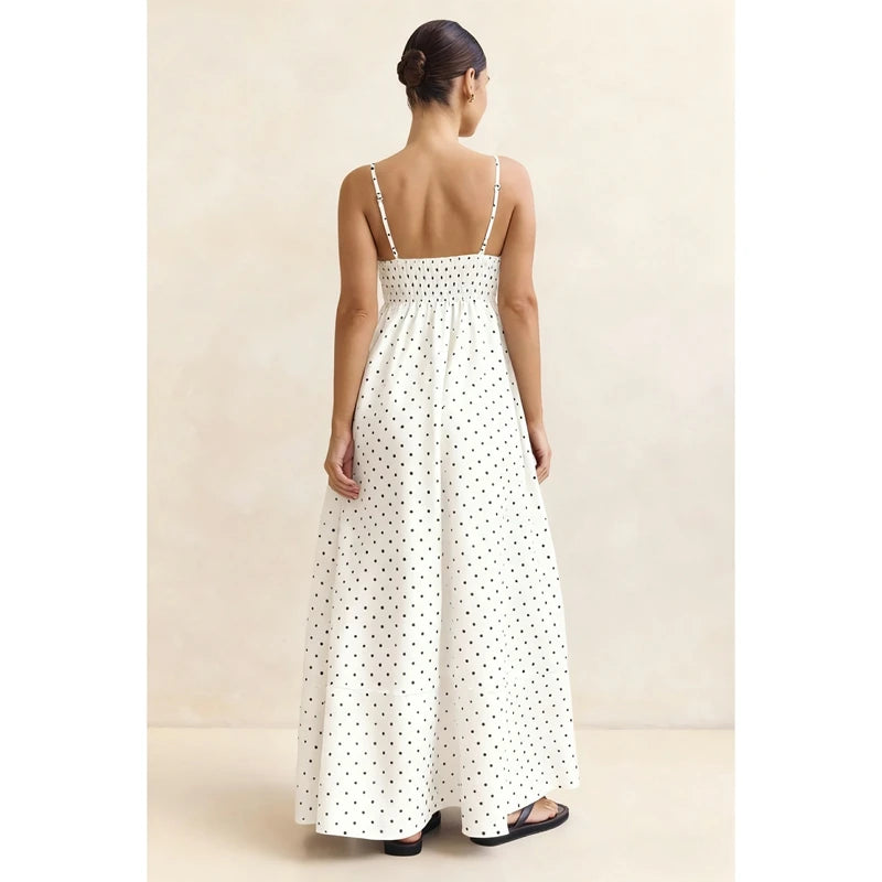 Woman wearing a white polka dot dress against a beige background