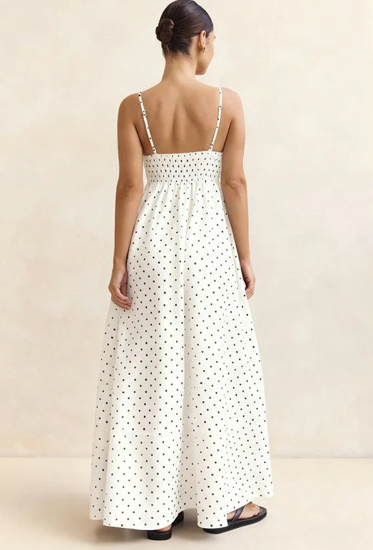 Woman wearing a white polka dot dress against a beige background