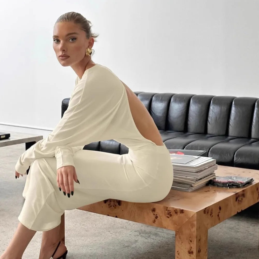 Woman in a white outfit sitting on a wooden coffee table in a modern living room.