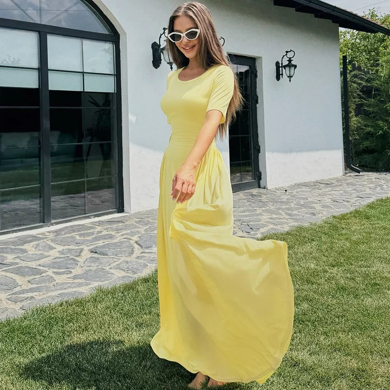 Woman in a yellow dress standing outdoors on a sunny day.