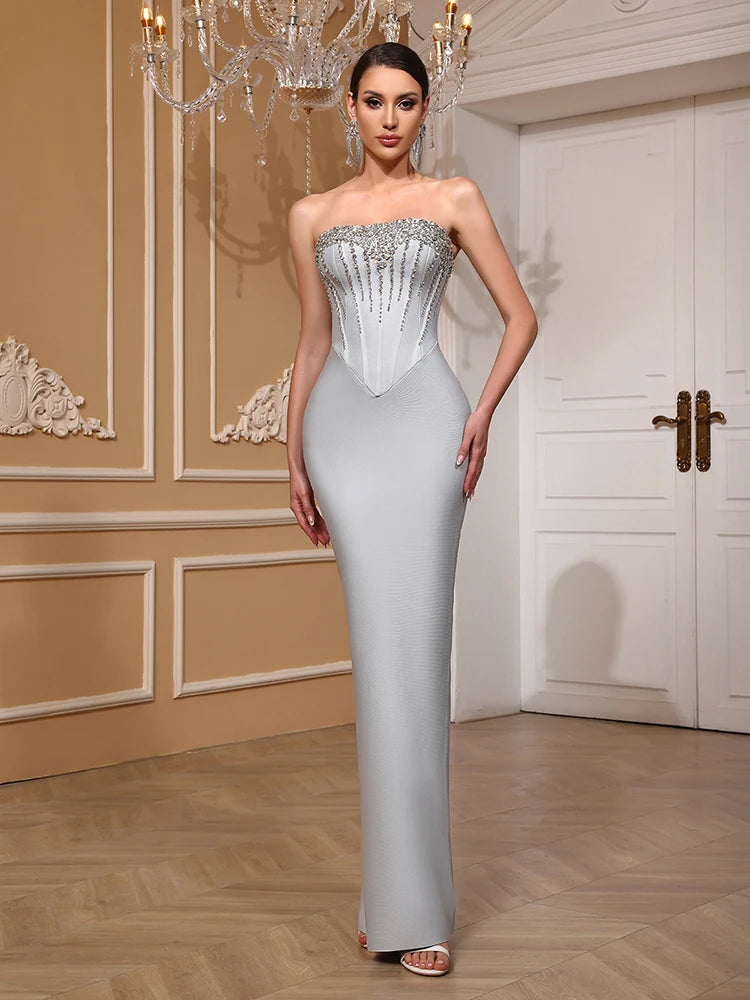 Woman in a strapless evening gown with intricate detailing in an elegant room.