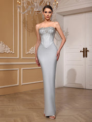 Woman in a strapless evening gown with intricate detailing in an elegant room.