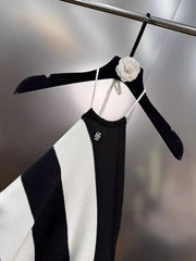 Black and white striped dress on a black hanger with a white flower against a metallic background