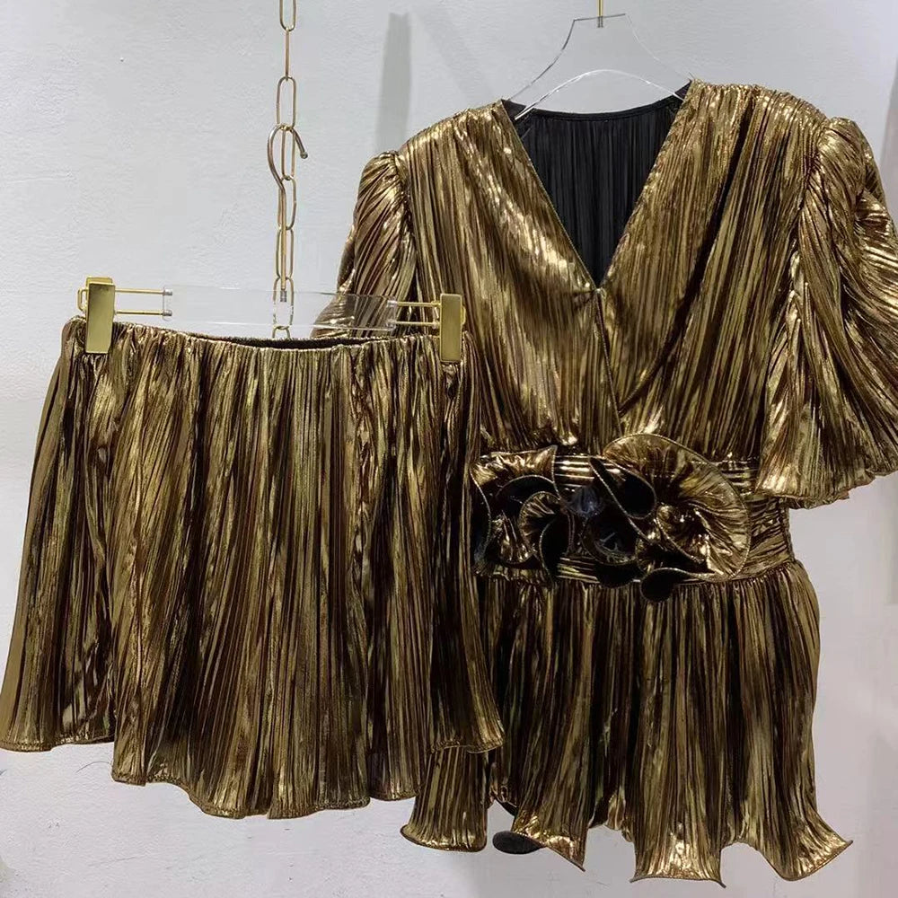 Gold pleated outfit on a hanger against a white background