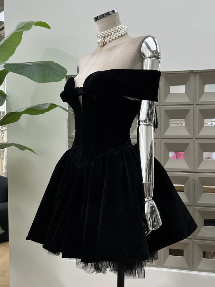 Black off-shoulder dress on a mannequin with pearl necklace against a light background