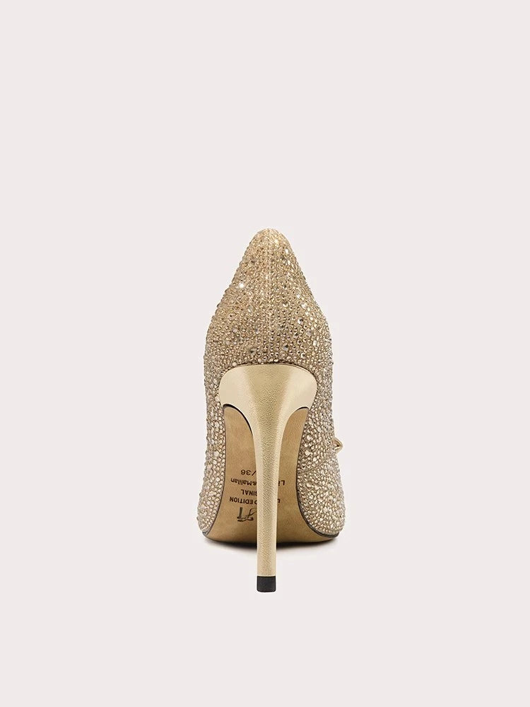 Gold stiletto heel shoe with rhinestone embellishments on a light gray background