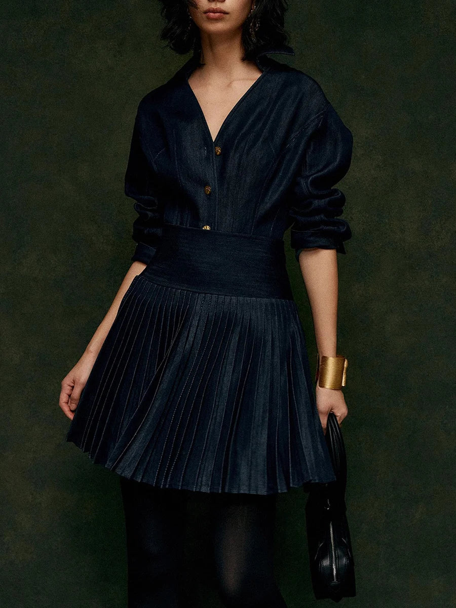 Woman wearing a dark blue pleated dress against a dark background