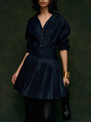 Woman wearing a dark blue pleated dress against a dark background