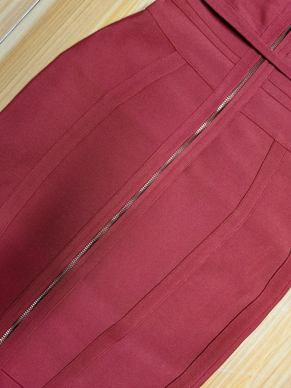 Close-up of a maroon skirt with a zipper on a wooden surface