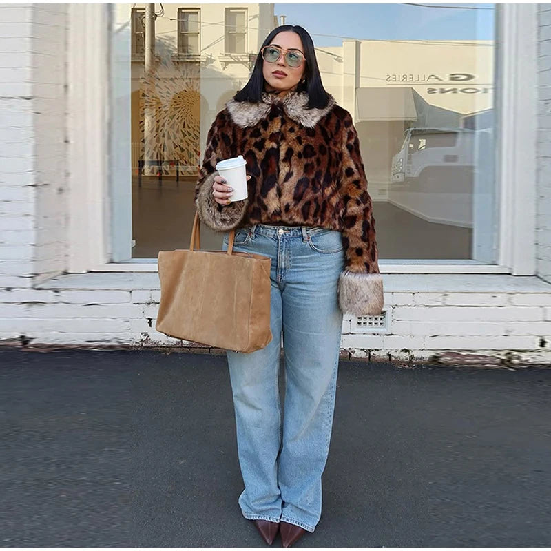 Person wearing a leopard print jacket and blue jeans, holding a beige tote bag, standing in front of a store.