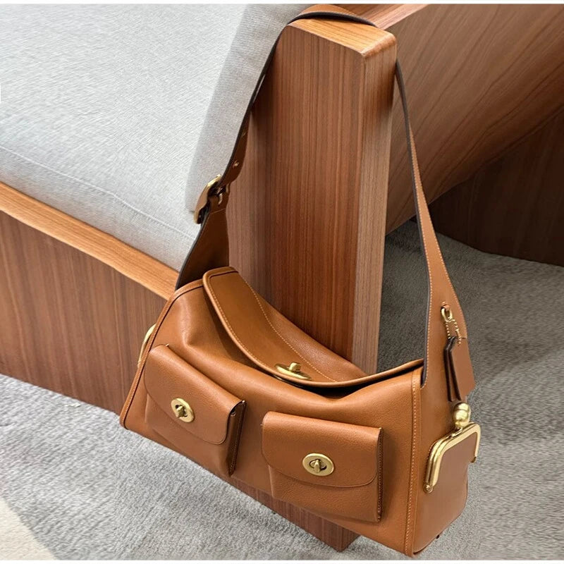 Brown PU leather shoulder bag with gold-tone hardware, displayed on a wooden chair.