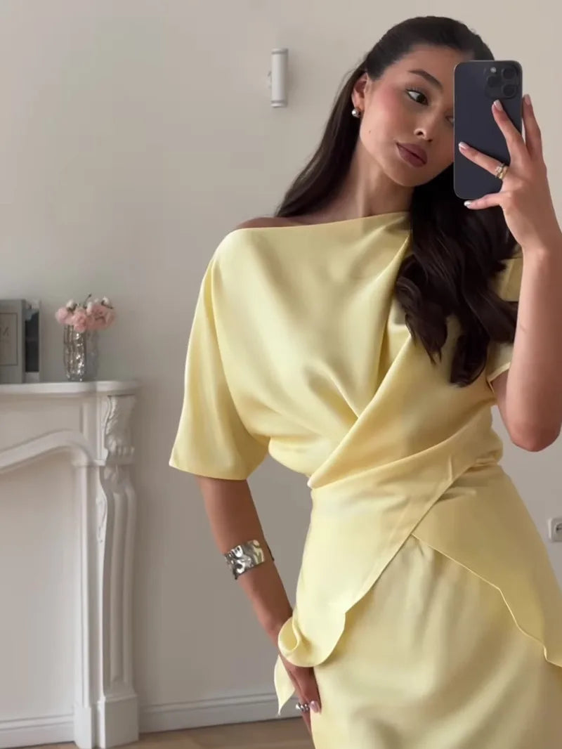 Woman in a yellow off-shoulder dress taking a mirror selfie.