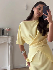 Woman in a yellow off-shoulder dress taking a mirror selfie.