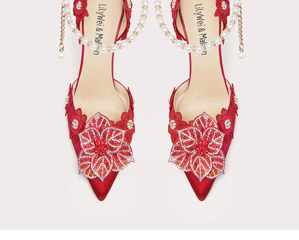 Red high-heeled shoes with floral embellishments on a white background