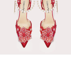 Red high-heeled shoes with floral embellishments on a white background