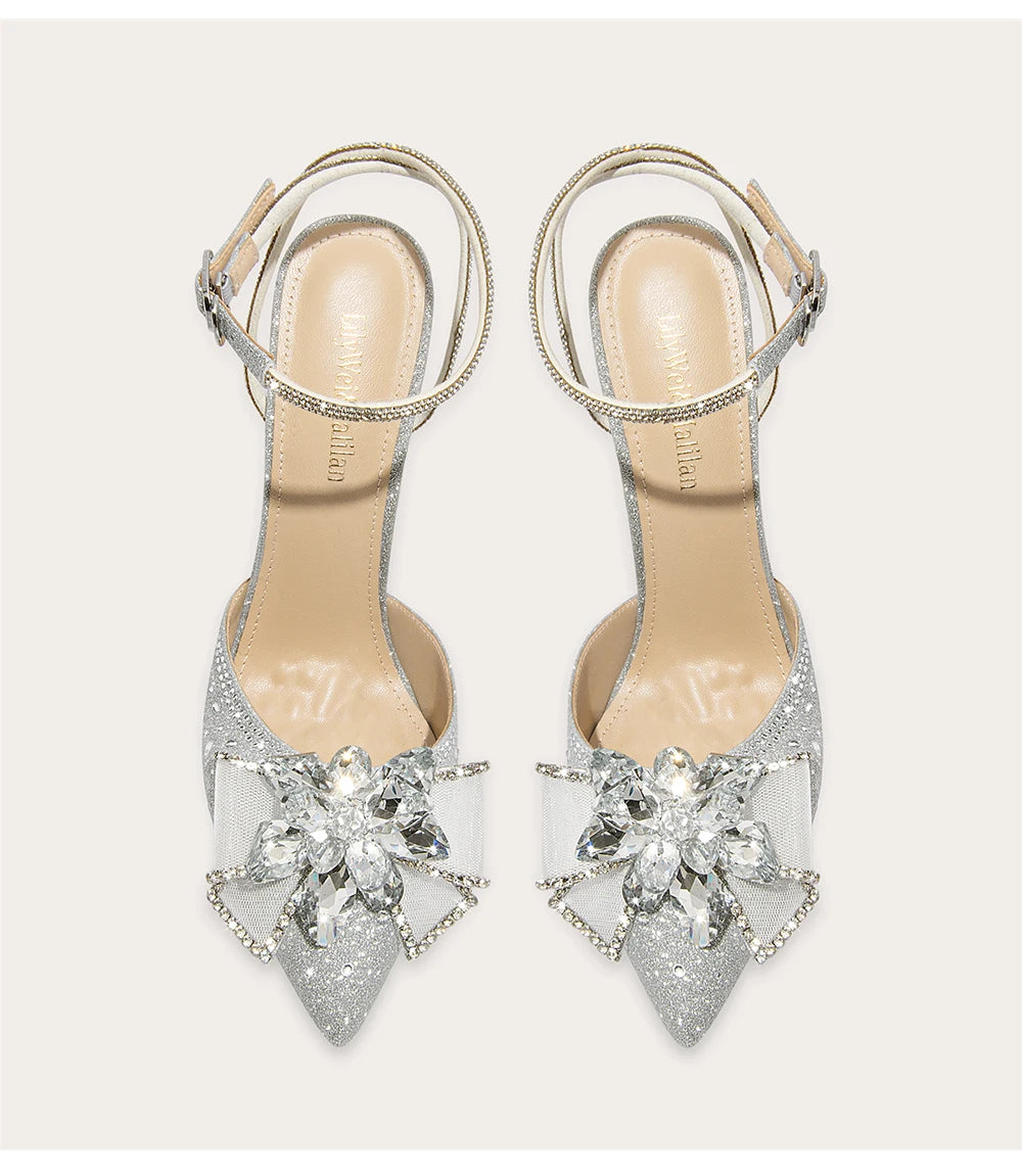 Silver high-heeled shoes with decorative crystal flowers on a white background