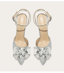 Silver high-heeled shoes with decorative crystal flowers on a white background