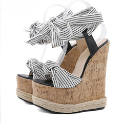 Wedge sandals with cork sole and striped ankle ties on a white background