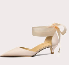 Beige high-heeled shoe with ankle strap on a light gray background
