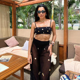 Black embellished bikini top and sheer cover-up pants on a person.