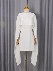 White dress with cape on a mannequin against a gray curtain background