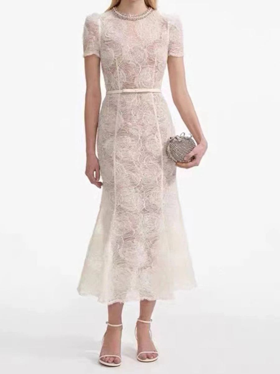 Woman wearing a lace dress holding a clutch on a white background