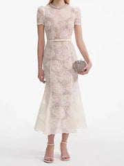 Woman wearing a lace dress holding a clutch on a white background