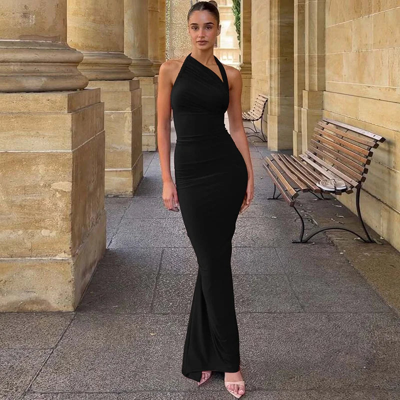 Woman in a black dress standing in an outdoor setting with columns and a bench.