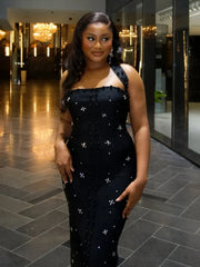 Woman in a black dress with white patterns standing in a hallway.