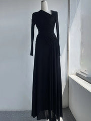 Black evening gown on a mannequin against a white wall.