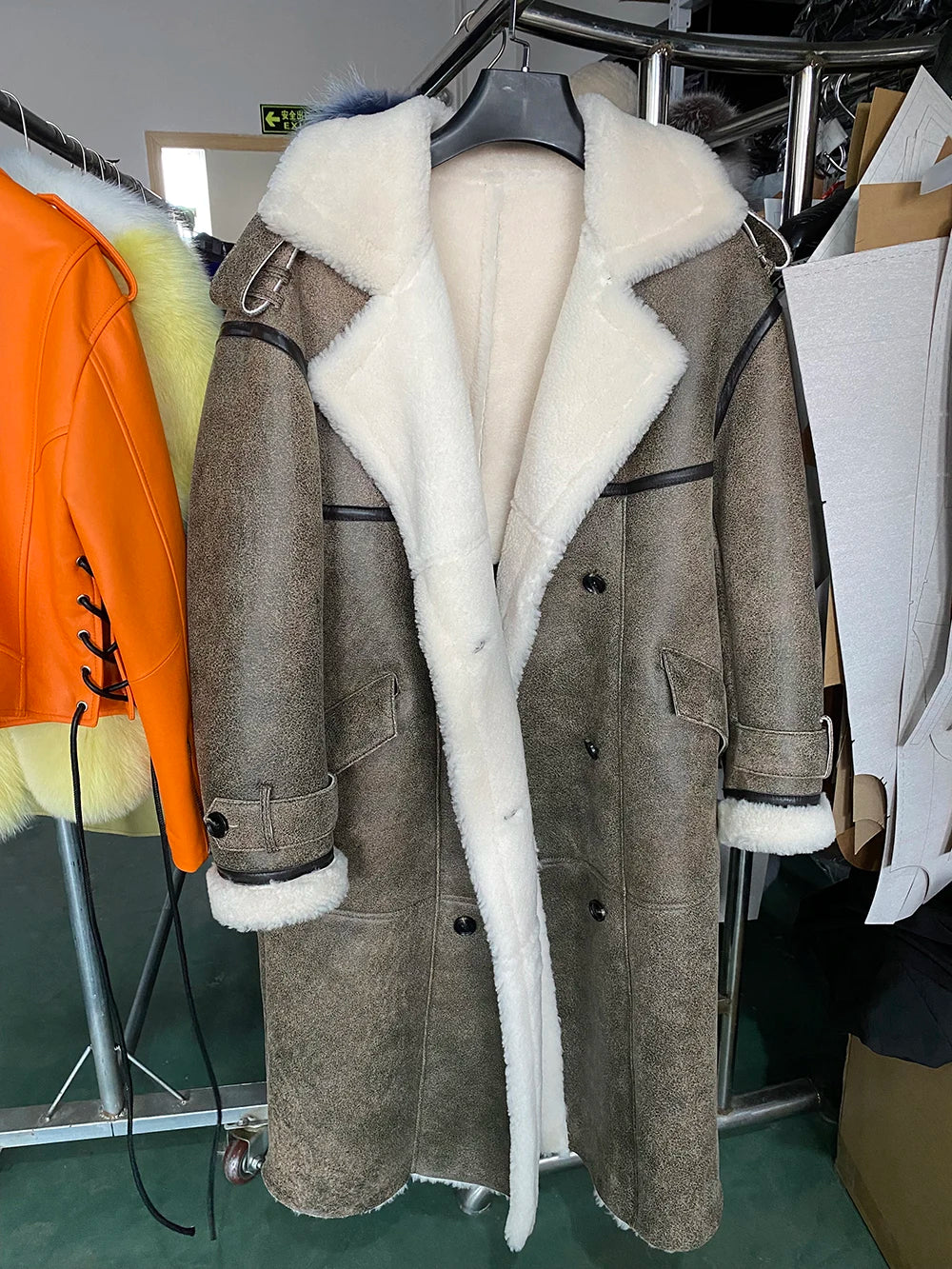 Gray coat with white fur lining on a hanger in a store setting