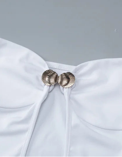 White strapless dress with gold bow detail on a gray background