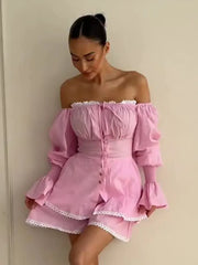 Woman wearing a pink off-shoulder dress with ruffled sleeves and hem against a plain background