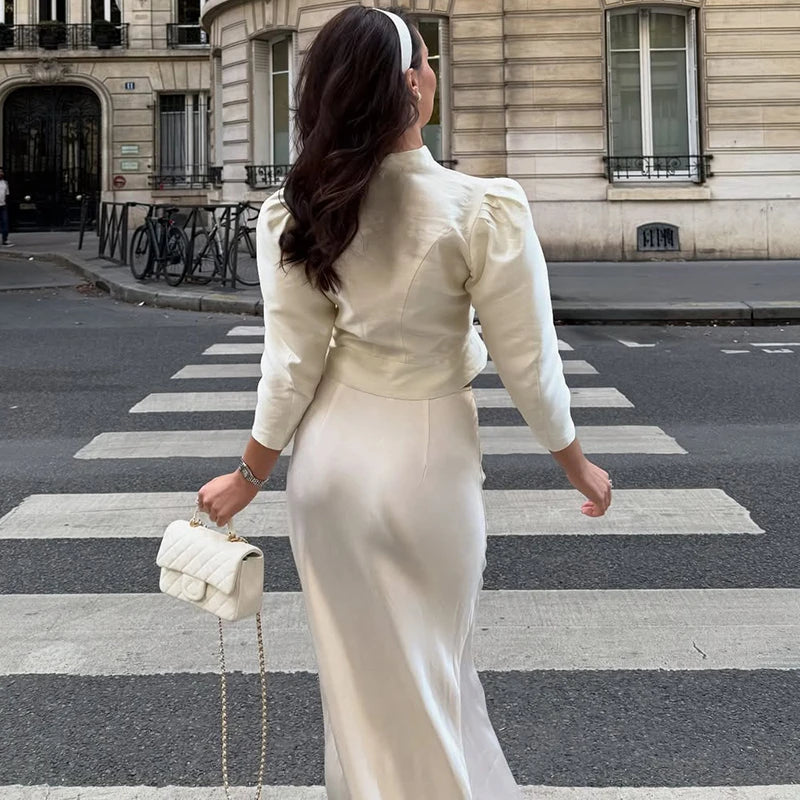 Woman in a white outfit crossing a zebra crossing in an urban setting
