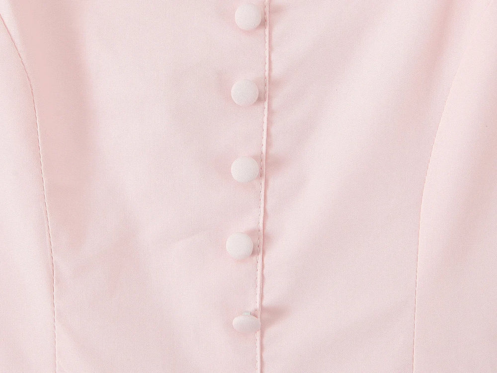 Close-up of a light pink garment with white buttons.