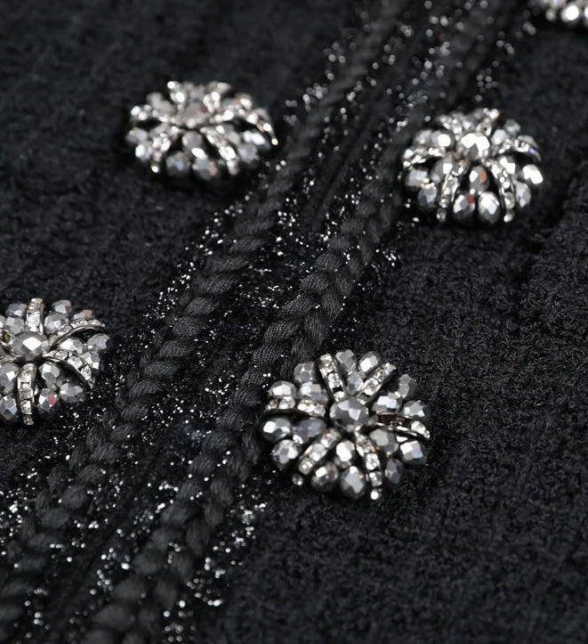 Close-up of black fabric with silver embellishments on a dark background