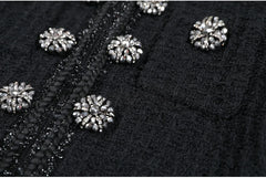 Close-up of black fabric with silver embellishments on a dark background