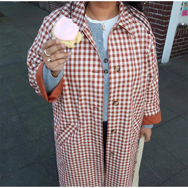 Person wearing a red and white checkered coat holding a pink ice cream.